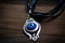 evil eye amulet, hanging from leather strap, with silver charm