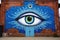 an evil eye mural painted on a brick wall in a city
