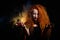 An evil red-haired witch holds fire in her hands.