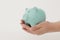 Ew blue piggy bank in female hands on a white background. Horizontal photo. Concept - saving money, investing
