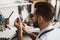 Exact size. Close up photo of a young male jeweler measuring ring with a tool in workshop.