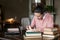 Exam preparation. Student girl in glasses and a pink sweater leaned over books, engaged in an old library at the table.