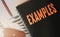 Examples word written on a copybook cover orange on black. Business and education concept. Selective focus