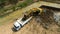 excavating soil into a dump truck to build a pond for store water for use in the dry season for agriculture, aerial top view