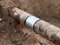 Excavation pit. Old drink water pipe with stainless repairing sleeve members.