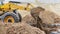 The excavator backfills the pit with the front bucket. Moves soil around the construction site. Close-up. Heavy construction