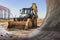 The excavator backfills the pit with the front bucket. Moves soil around the construction site. Close-up. Heavy construction