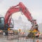 Excavator and barricades with yellow tape on a muddy mountain road in winter