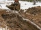 The excavator bucket digs a pit trench for laying engineering electrical communications and cables