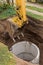 Excavator with a bucket, lowering into the pit on steel cables concrete sewer ring. Construction or repair of sewer home