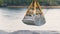 Excavator bucket scoops the gravel from the iron container on the background of the river