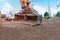 Excavator bucket on top of gravel with concrete pump in background awaiting concrete delivery