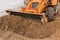 Excavator or bulldozer bucket flattens the ground or road in the industrial zone or construction site