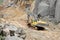 An excavator carrying a oil drum in a granite mine