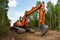 Excavator clearing forest for new development. Orange Backhoe modified for forestry work. Tracked heavy power machinery for forest