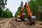 Excavator clearing forest for new development. Orange Backhoe modified for forestry work. Tracked heavy power machinery for forest