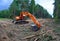 Excavator clearing forest for new development. Orange Backhoe modified for forestry work. Tracked heavy power machinery for forest