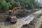 Excavator clears debris from road due to flooding