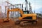 Excavator close-up of dripping scoop of earth on construction site of electrical station with industrial equipmen