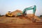 Excavator and compactor are on a large pile of soil.
