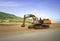 Excavator on a construction site, next to a hill