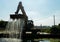 An excavator crane removes debris and algae build up from the Naviglio Pavese canal on a sunny day.