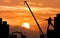 Excavator and crane working sunset background