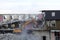 Excavator demolishes a residential high-rise building. The floors are broken, litter is lying around, dust is flying. The ruins of