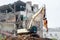 Excavator demolishing a brick building. Machinery Demolishing Building