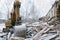 Excavator demolition log wooden house in snowfall