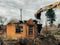 Excavator destroying brick house on land in countryside. Bulldozer clearing land from old bricks and concrete from walls with dirt