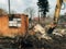 Excavator destroying brick house on land in countryside. Bulldozer clearing land from old bricks and concrete from walls with dirt