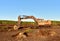 Excavator digging drainage ditch in peat extraction site. Drainage of peat bogs and destruction of trees. Drilling on bog for oil