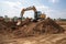 excavator digging into pile of freshly dug earth, ready to build new foundations
