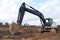 Excavator digs dirt during roadwork at construction site. Heavy machinery and earth-moving equipment