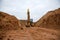 Excavator digs a large trench for pipe laying. Backhoe during earthmoving at construction site. Earth-moving heavy equipment