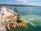 An excavator diligently constructs a dock or breakwater in the sea, its mighty arm reaching out from the shore, creating