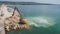 An excavator diligently constructs a dock or breakwater in the sea, its mighty arm reaching out from the shore, creating