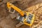 Excavator on the ground of a construction site with a raised bucket, top aerial view