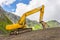 Excavator heavy equipment in mountains on steep range slopes