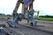 Excavator with hydraulic shears breaks asphalt on a construction site.