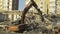 Excavator with an iron tentacle grabs pieces of reinforcement, being on the ruins of a destroyed building