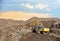 Excavator at landfill for the disposal of construction waste. Backhoe digs gravel and concrete crushing. Recycling old concrete