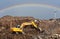 Excavator at landfill on rainbow background in sky. Disposal of construction waste and concrete crushing. Recycling old concrete