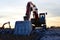 Excavator with a large iron bucket breaks asphalt on a construction site.