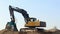 Excavator with a large screening bucket on a gravel ground.