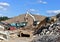 Excavator load concrete waste into a mobile jaw crusher machine at at landfill. Disposal of construction waste. Recycling concrete