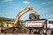 excavator loading dumper trucks at garbage dumping site