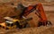 Excavator loading sand into dumper truck.