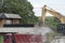 Excavator loads construction waste into a red truck. Destroyed concrete, construction waste.